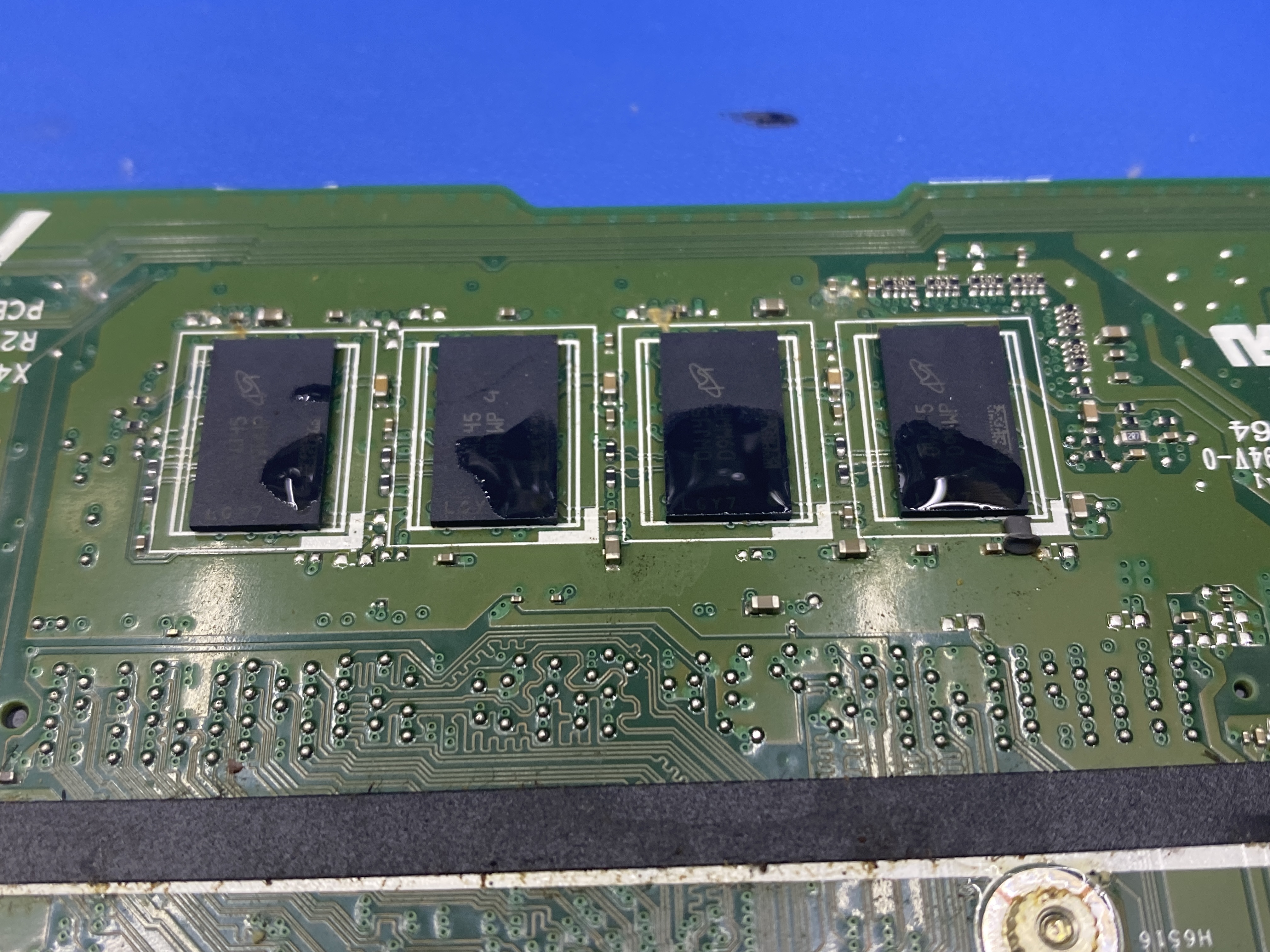 Štyri pamäťové čipy základnej dosky ASUS X515JP so stopami kvapaliny pred čistením