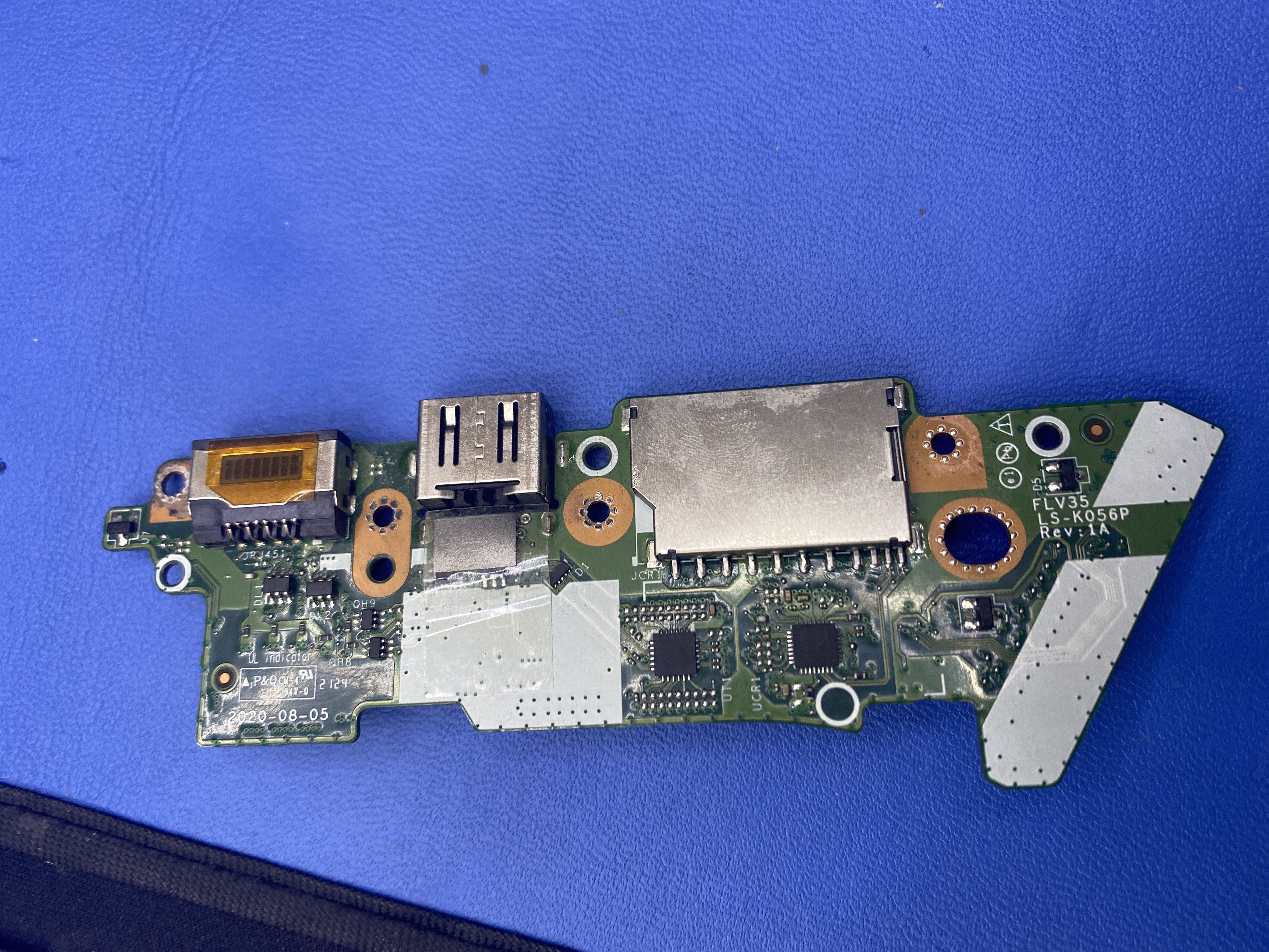 Demontovaná ľavá I/O dcérska doska s USB portami a čítačkou kariet pripravená na kontrolu oboch strán.