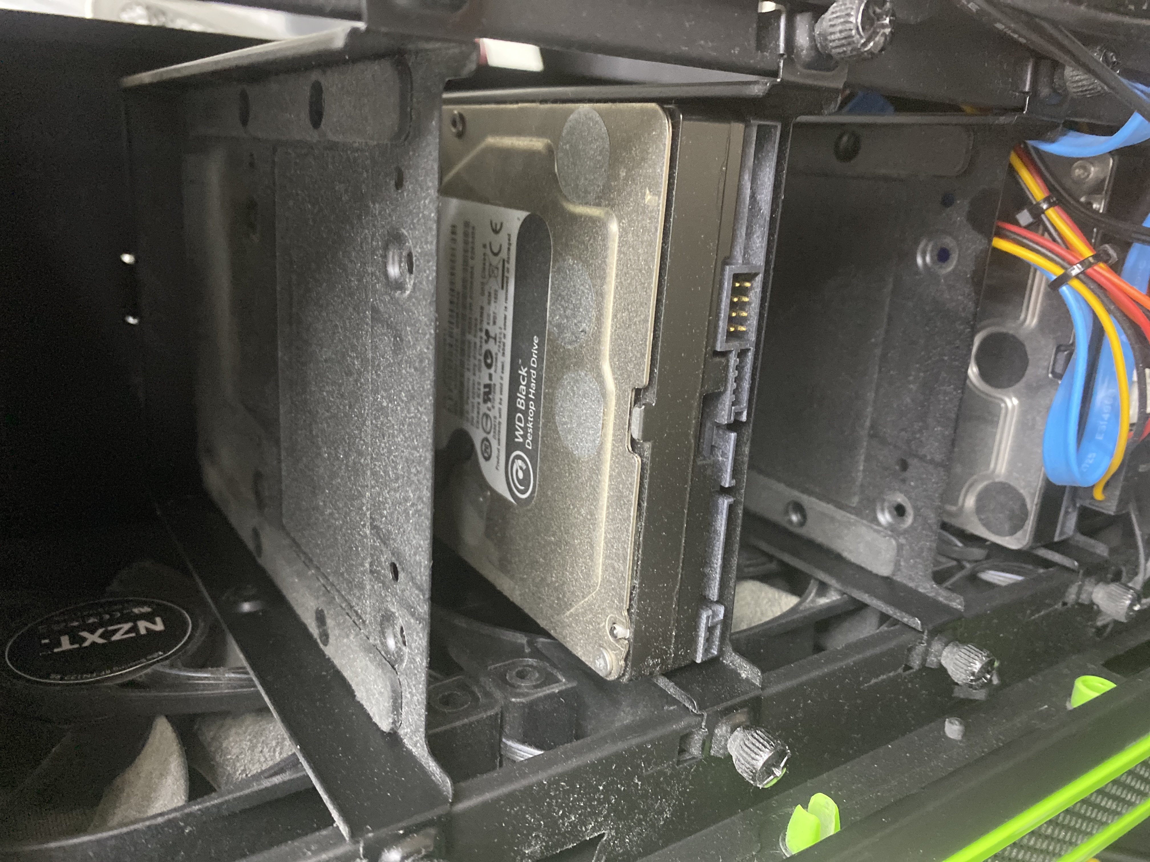 WD Black Desktop Hard Drive v spodnom diskovom koši; na disku, koši a okolí je viditeľná vrstva prachu.