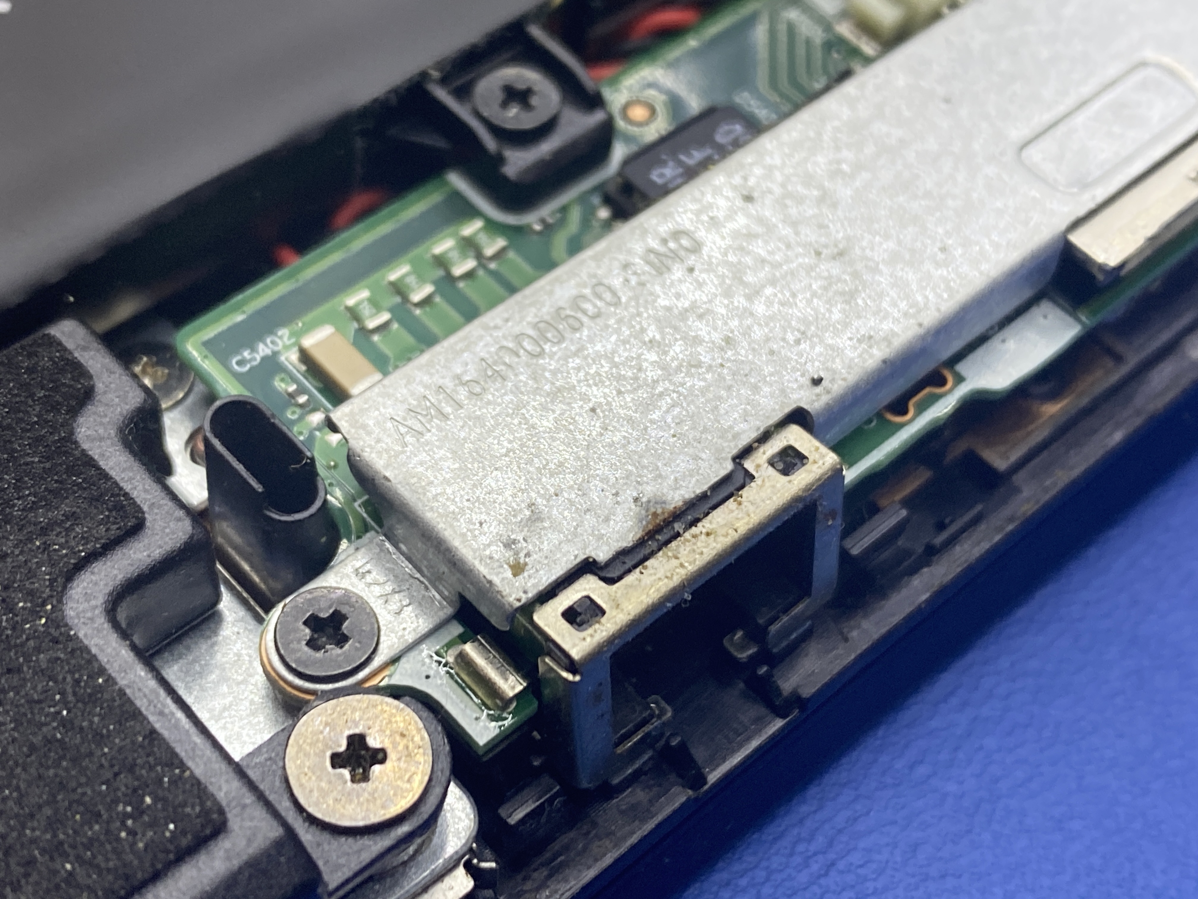 Detail poškodeného USB-C konektora na základnej doske pred opravou.